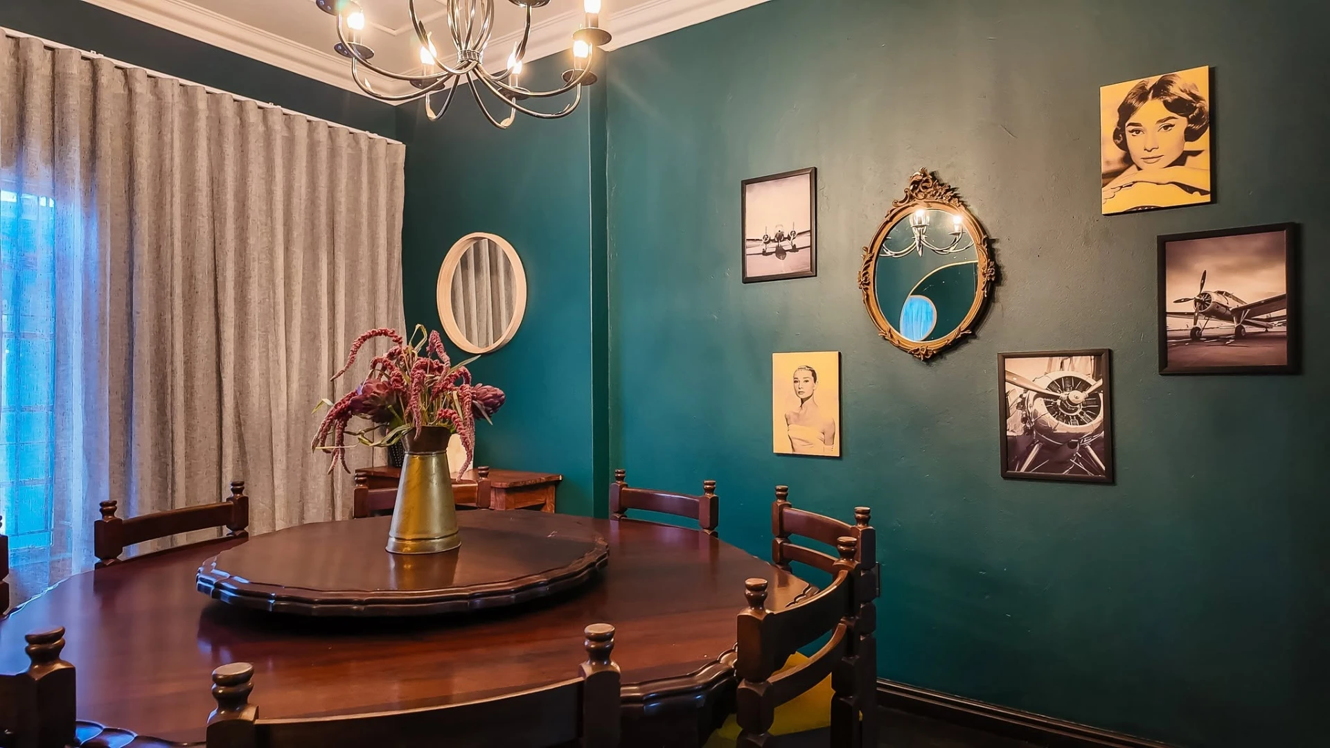 Intimate dining room with teal walls and vintage art